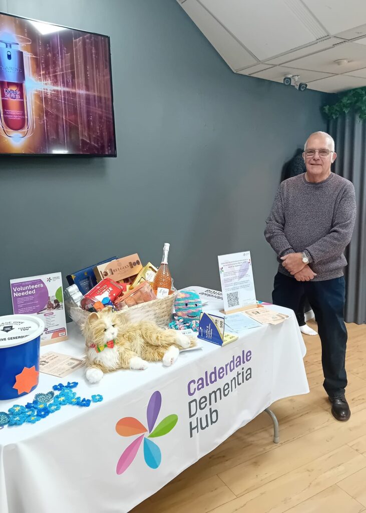 A Volunteer stands at a fundraising stall selling raffle tickets.